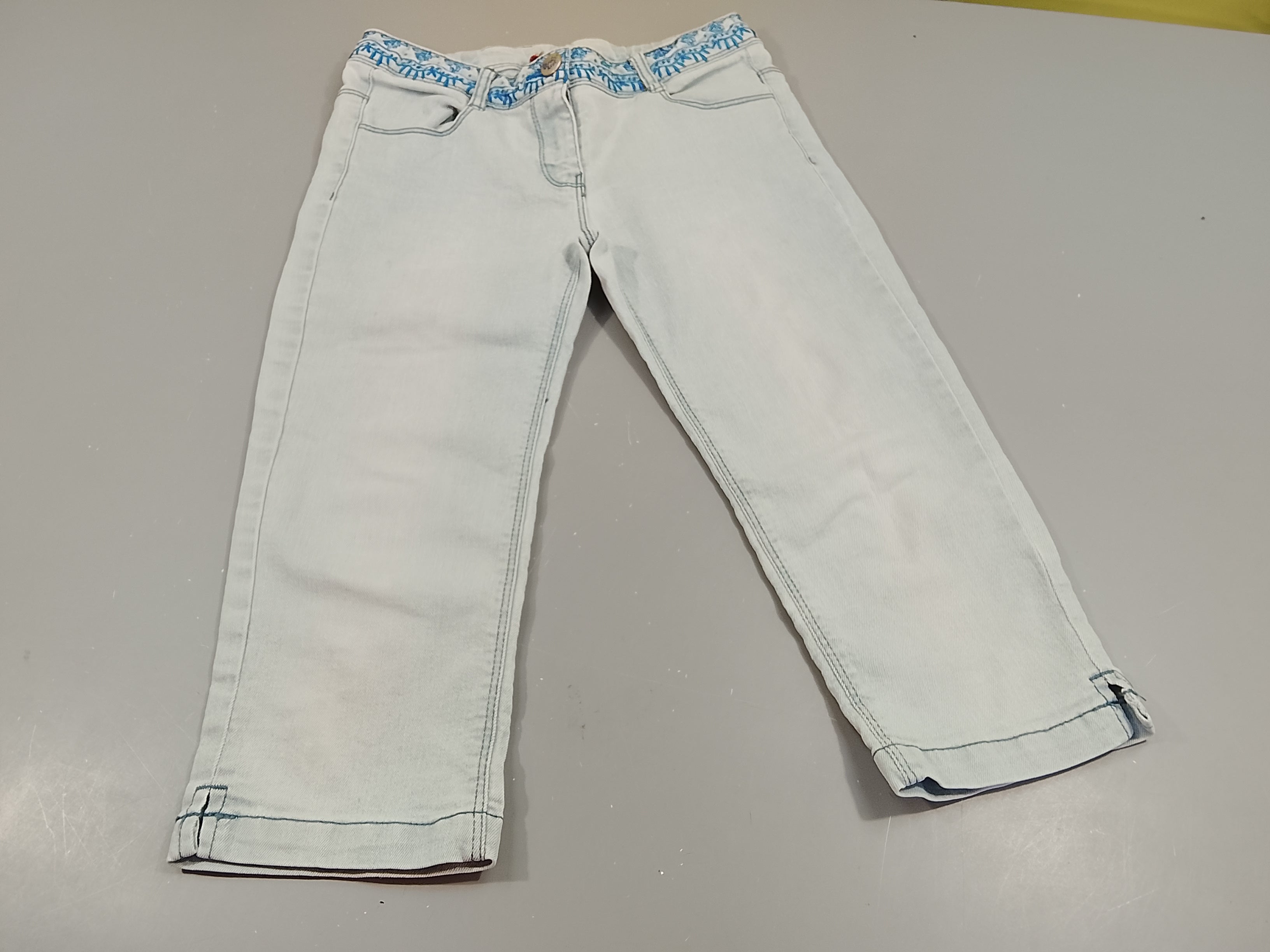 Pantacourt en denim clair, broderies à la taille. Très légère tache